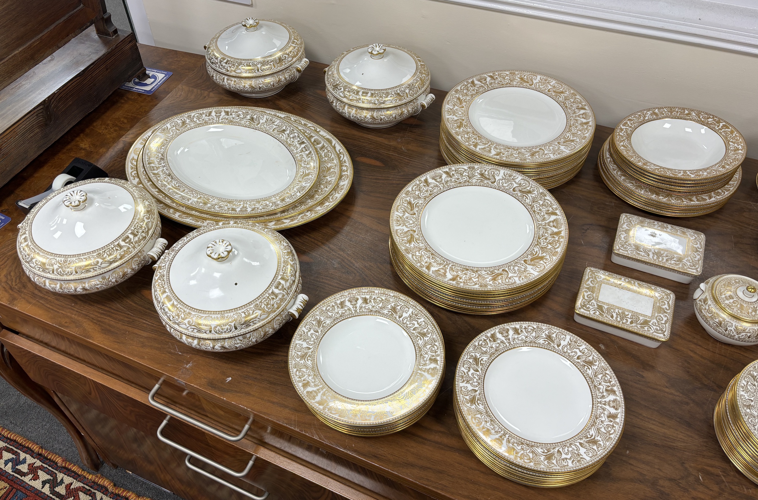 An extensive Wedgwood Gold Florentine dinner service, including 26 dinner plates, 50 side plates, 18 soup bowls with 16 saucers, 6 tea cups and 4 saucers, 6 bowls, 6 large cheese plates, 5 gravy boats and 3 saucers, 3 ve